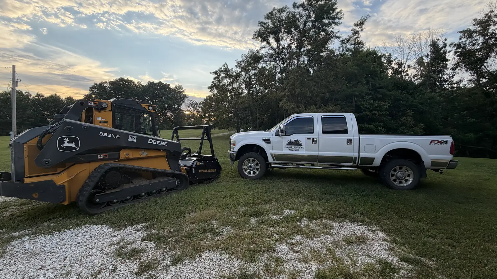 Mid Missouri Forestry Mulching truck parked beside the Deere 333P mulcher at sunset