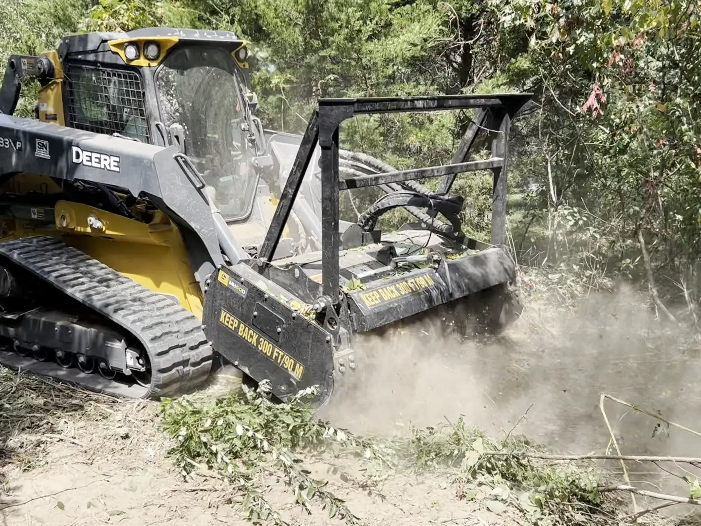 Deere 333P forestry mulcher working through a cedar thicket in a cloud of dust