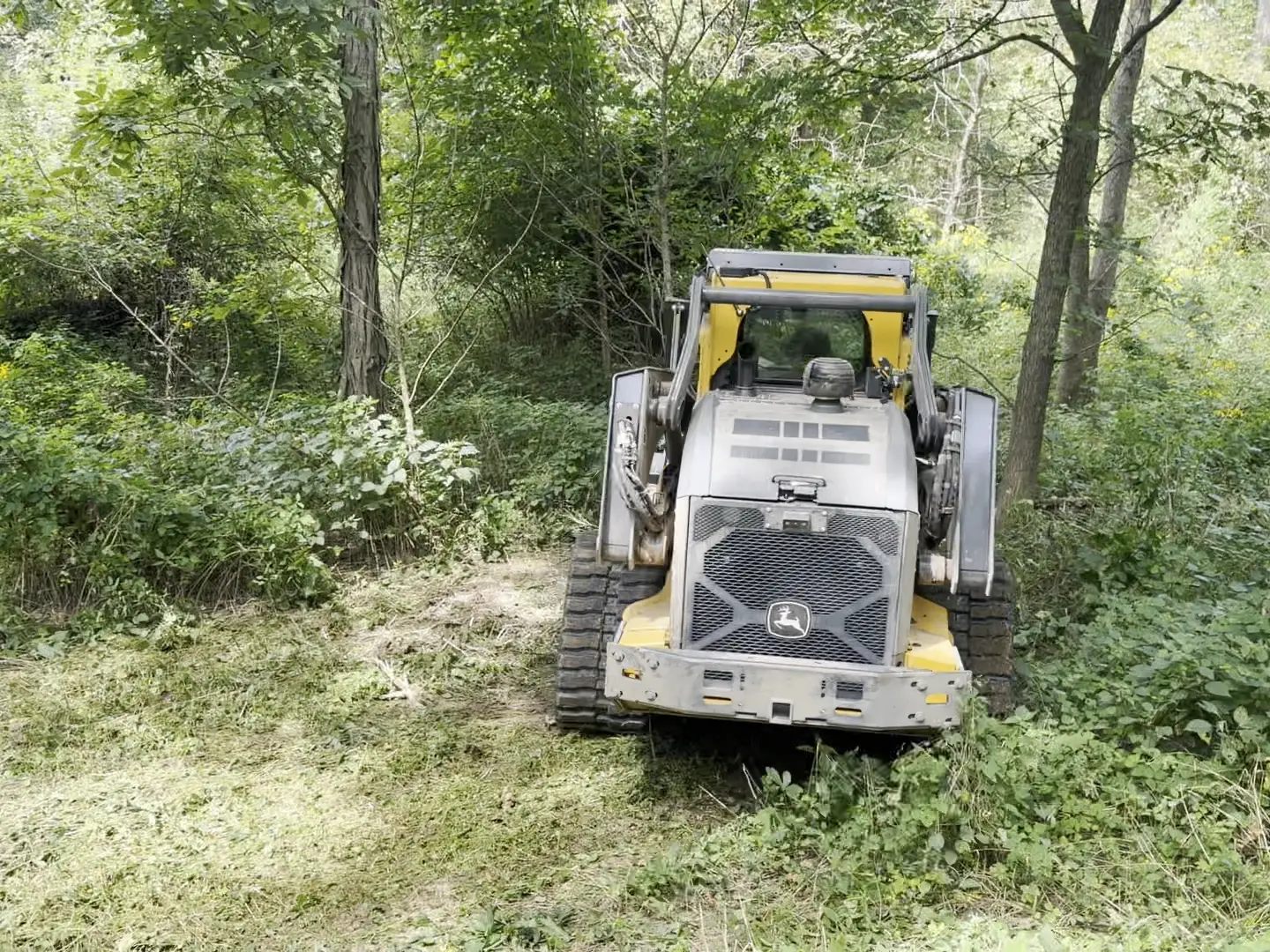 Deere 333P mulcher sitting on a freshly mulched lane through the woods