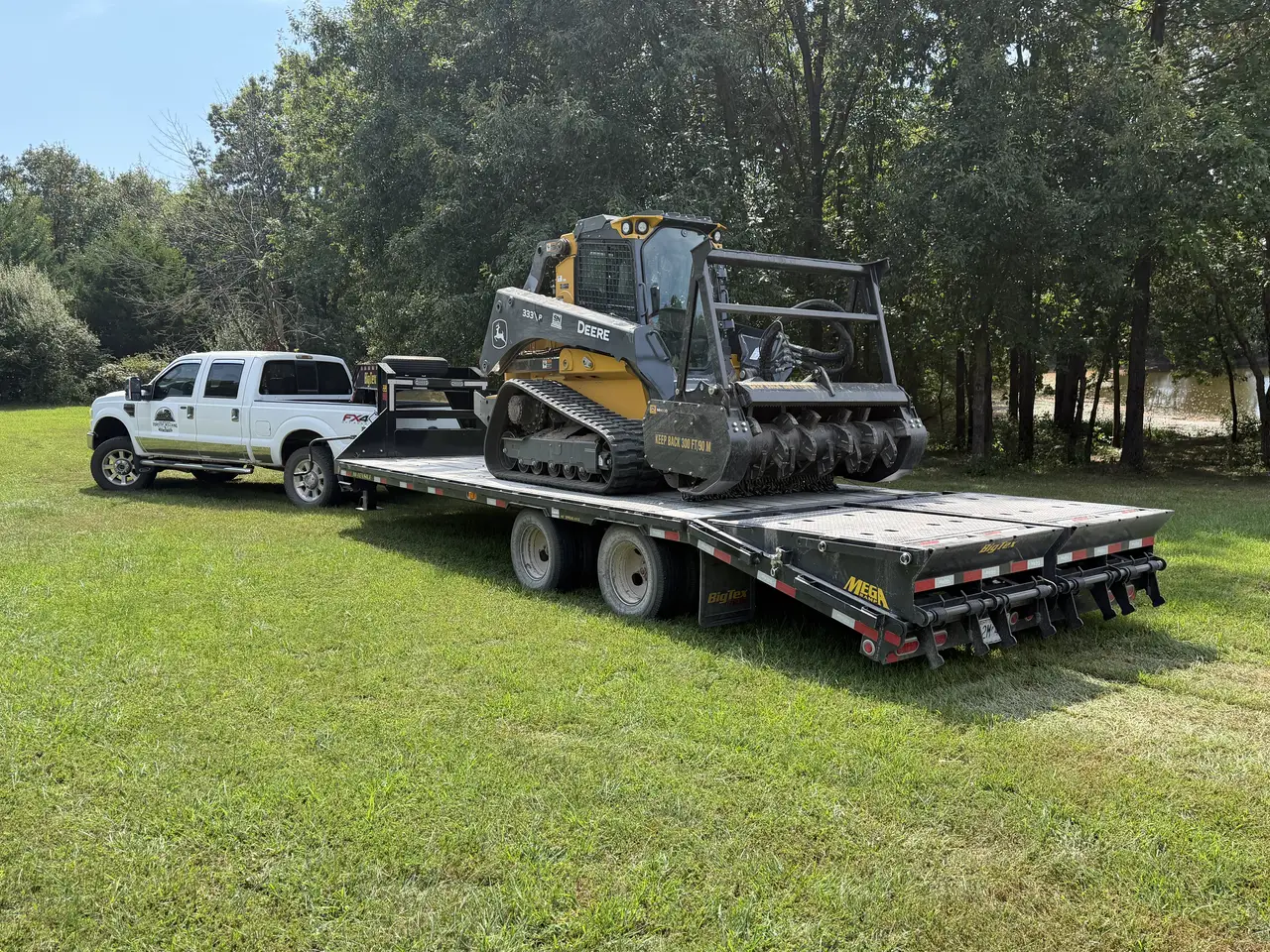 Deere 333P forestry mulcher chained down on the gooseneck trailer