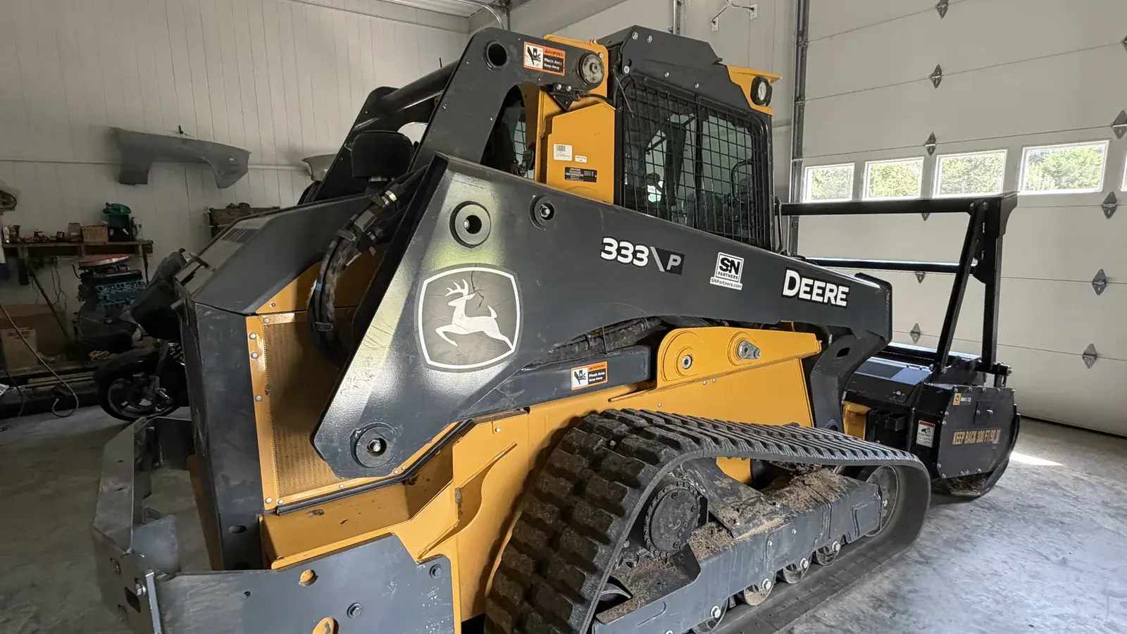 The Mid Missouri Forestry Mulching track loader with its mulching head in the shop
