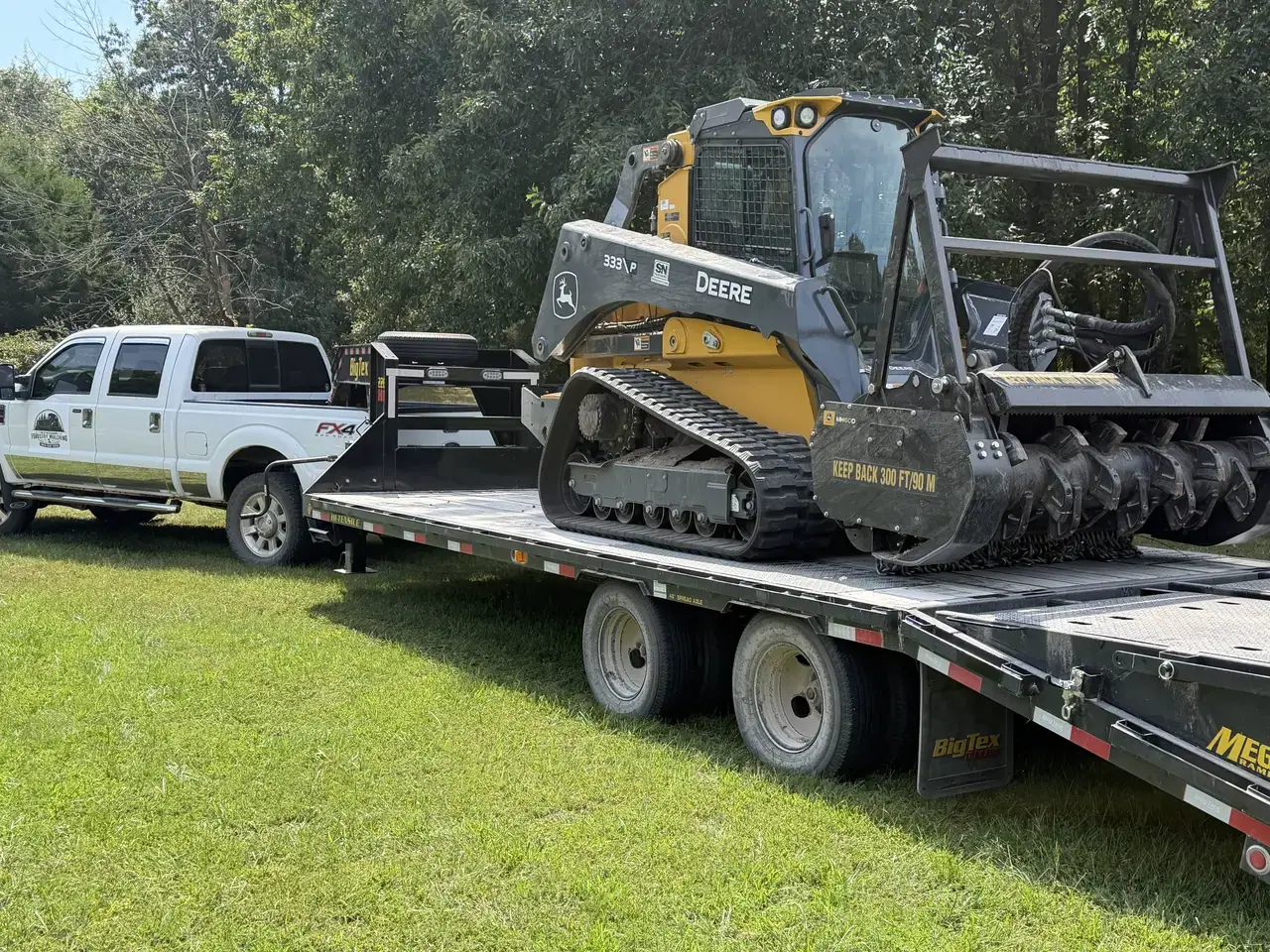 Forestry mulcher loaded on the gooseneck trailer behind the company truck